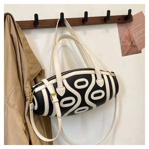 Detail of a black and white barrel bag with wavy leather texture and gold hardware