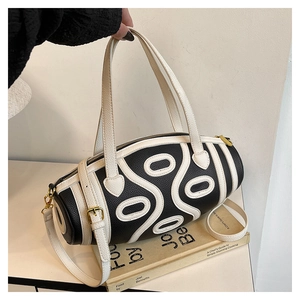 Detail of black pebbled leather cylinder bag with white wave pattern and gold hardware