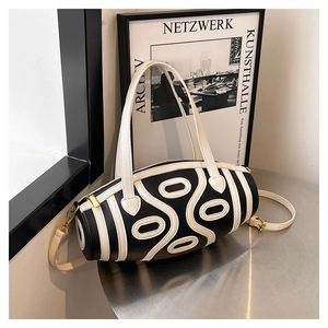 Detail of a cylinder leather bag with black and white stripes on a modern metal table