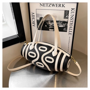 Detail of lychee textured leather cylinder bag with geometric patterns and gold hardware