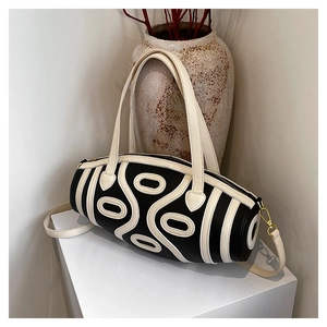 Close-up of black lychee grain leather cylinder bag with white wave pattern details