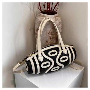 Detailed close-up of a black and white geometric Boston bag with golden hardware