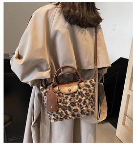 Detail view of leopard print plush bag showing leather handles and flap with embossed text