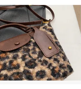 Detail of leopard print faux fur handbag with brown leather handles and gold studs