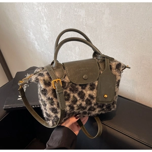 Detailed view of leopard print faux fur handbag with dark green leather handle and gold hardware