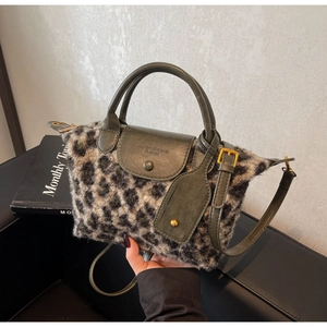Close-up of leopard print plush tote bag with dark green leather strap and gold clasp detail