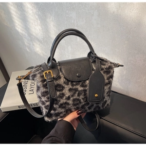Detail of leopard print faux fur handbag with black leather flap and cylinder handles