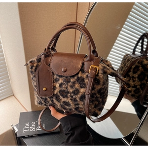 Detail of leopard print plush handbag with brown leather straps and metal buckles