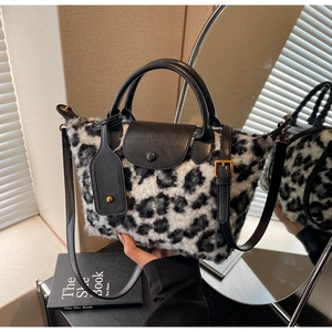 Detail of plush leopard print handbag with black leather trim and embossed brand logo