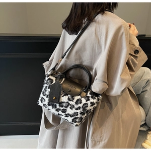 Close-up of fluffy leopard print handbag texture with black leather handle on a trench coat