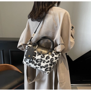 Detail of plush leopard print handbag with black leather handle and strap on model