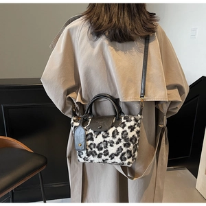 Detail of leopard print faux fur handbag with black leather strap and metal hooks
