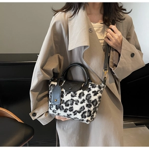 Detail of leopard print faux fur crossbody bag with black leather flap and shoulder strap