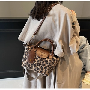 Detail of leopard print plush handbag with brown leather handle and shoulder strap