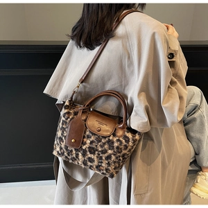 Detail of leopard print faux fur handbag with brown leather flap and metal snap closure