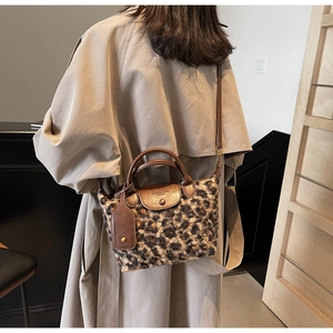 Close-up of leopard print faux fur crossbody bag with brown leather strap and metal buckle
