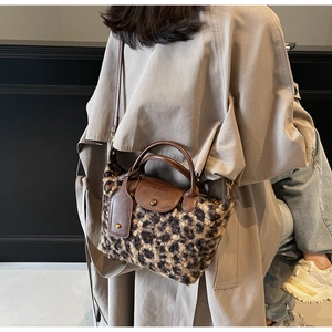 Detail of leopard print plush handbag with brown leather flap and long crossbody strap
