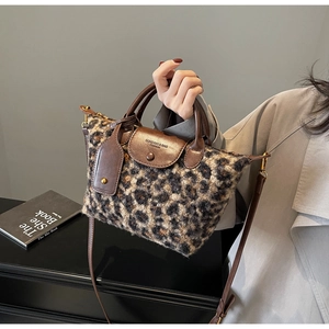 Detail of leopard print plush handbag featuring leather strap and flap with branding