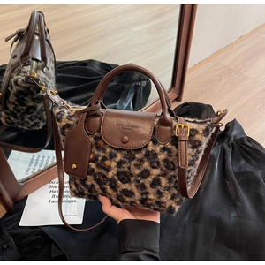 Close-up of leopard print plush handbag featuring dark brown leather straps and detail