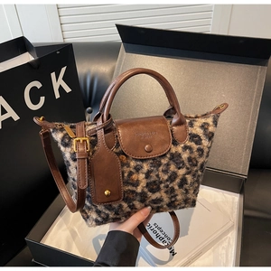 Detail of leopard print plush tote bag with brown leather handles and branding tag