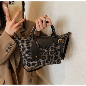 Close-up of leopard print plush handbag with black leather flap and gold hardware detail