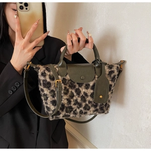 Mirror selfie showing the medium-sized leopard print plush tote bag with green leather trim