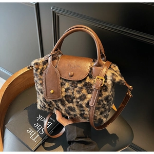 Detail of leopard print plush handbag with brown leather flap and adjustable strap