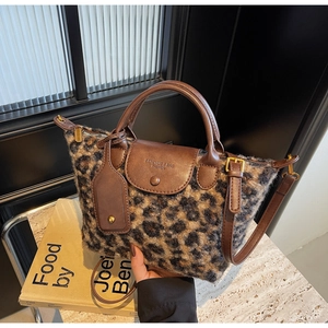 Detail of leopard print faux fur handbag with brown leather flap and adjustable strap