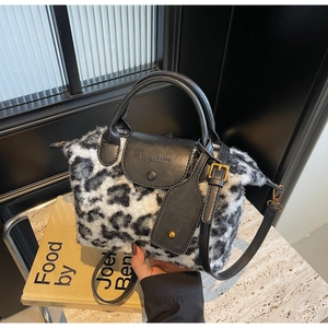 Detail of plush leopard print faux fur texture with black leather handle and gold hardware