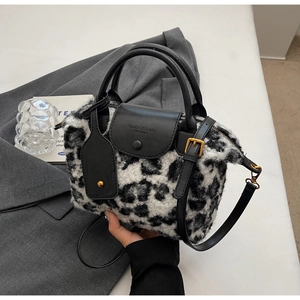 Detail of leopard faux fur tote featuring black leather handles and branded flap cover
