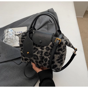 Close-up of leopard print plush texture and black leather strap on a shoulder bag
