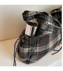 Detail of checkered shoulder bag featuring functional drawstring side pocket for water bottle