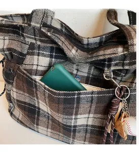 Detail of wool plaid tote bag front pocket with vintage check pattern and wooden bag charm