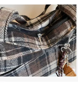 Detail view of smooth silver metal zipper on classic plaid wool tote with baseball charm