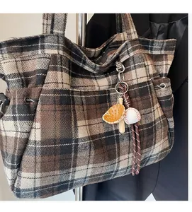 Detail of wool plaid tote bag featuring brown check pattern and baseball themed charms