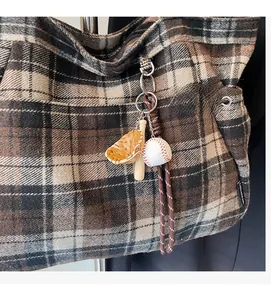 Detail of baseball theme charm with wooden bat and leather glove on plaid tote bag