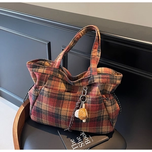 Detail view of vintage plaid tote bag with wool texture and baseball glove charm