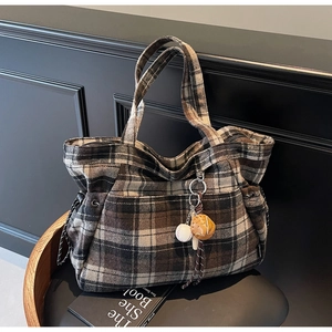 Detail of vintage plaid tote bag with baseball charm on a wooden chair