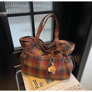 Detail of vintage plaid tote bag featuring woolen texture and a cute brown bear charm