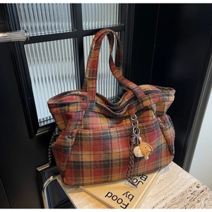 Macro shot of plaid wool tote bag with drawstring side pockets and baseball charm