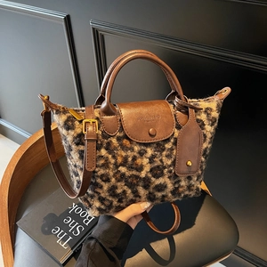 Vintage leopard print plush handbag with brown leather straps on a black chair