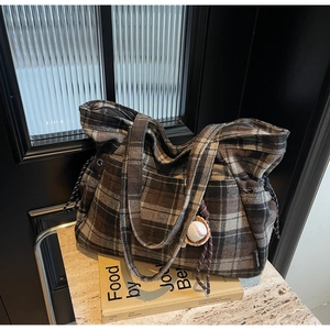 Close-up of vintage plaid tote bag with baseball charm on marble surface