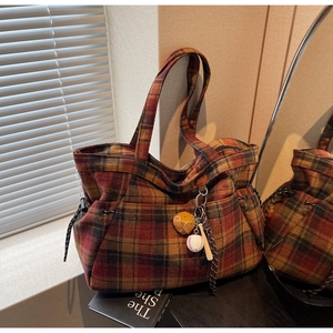 Detail of wool plaid tote bag with baseball charms and side drawstring adjustment