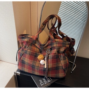 Detail of plaid tote bag with baseball charms and drawstring pocket on a vanity