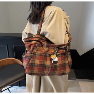 Detail view of wool plaid tote bag with side drawstring and floral charm accessory