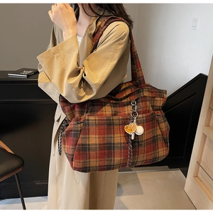 Detail of a large plaid wool tote bag with baseball pendant accessory and shoulder strap