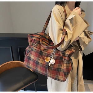 Detail of vintage plaid tote bag with wool texture and baseball glove charm accessory