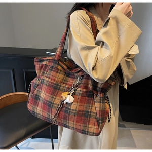 Detail of a large tartan plaid tote bag with baseball charm and long shoulder strap