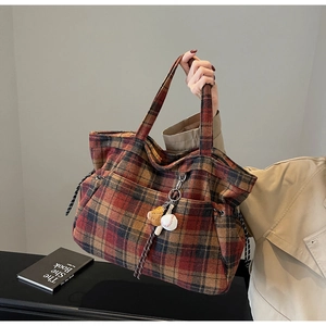 Close-up of retro plaid wool tote bag featuring a baseball glove charm and textured finish