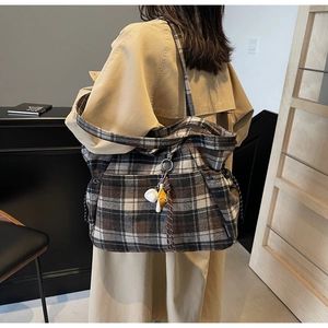 Detail view of large checkered plaid tote bag with baseball charm on a shoulder strap